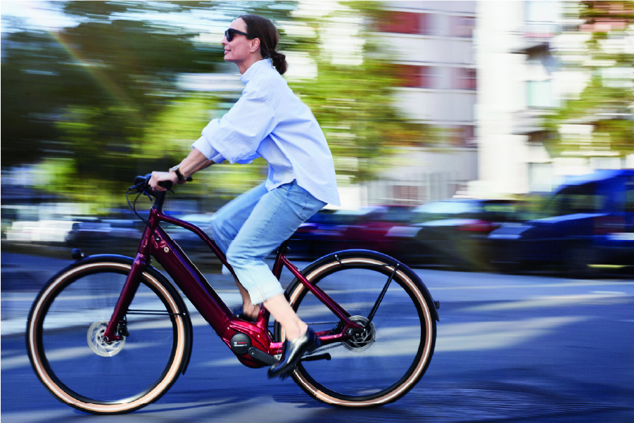 Frau fährt mit Schindelhauer Hannah in Farbe granatrot durch die Stadt
