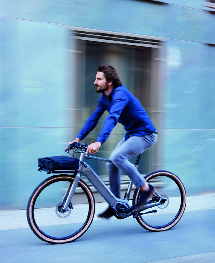 Man fährt mit Schindelhauer Heinrich in Farbe titansilber auf der Straße mit seiner Tasche auf den Gepäckträger