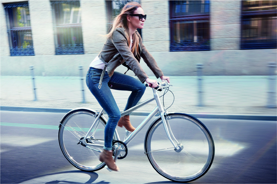 Frau fährt mit Schindelhauer Lotte in Farbe alu pur durch die Stadt