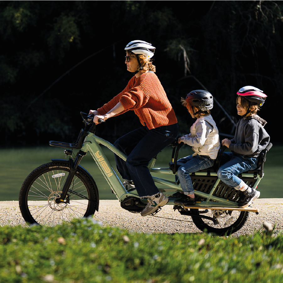 Eine Frau transportiert ihre Kinder mit Yuba Spicy Curry in Farbe Lunar durch die Stadt.