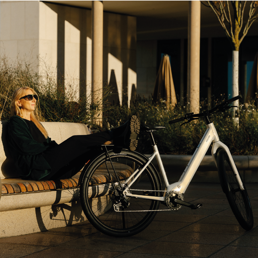 Frau sitzt auf einer Bank mit Coboc Sky Step in weiß neben sich im Park