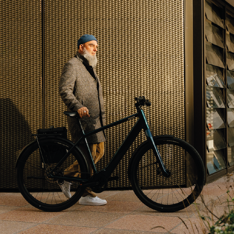 Man steht mit dem Fahrrad Coboc Sky in ocean metallic blau an seiner Seite